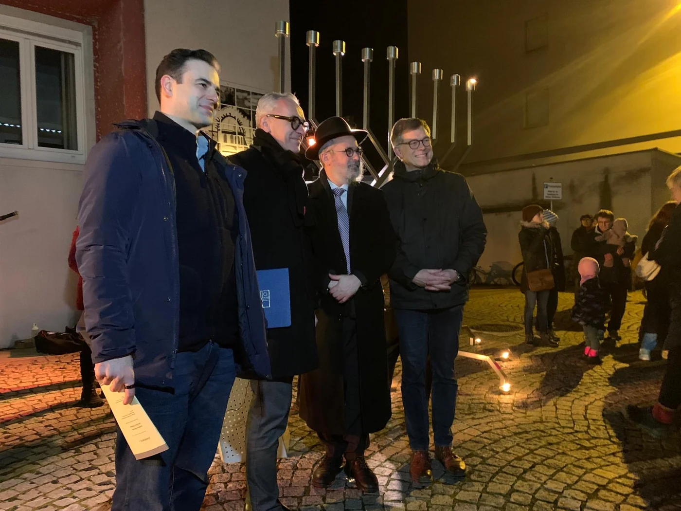 Teilnehmer der Chanukka-Feier vor dem Leuchter mit brennenden Kerzen an der Alten Feuerwache in Bruchsal